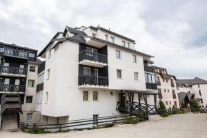 a white building with black balconies on it at Apartman No.32a-JollyKop in Kopaonik