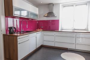a kitchen with white cabinets and pink walls at Casa Cambodunum in Kempten