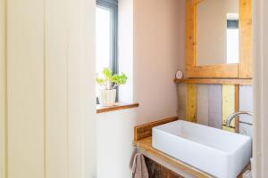 a bathroom with a white sink and a mirror at The Old Butchers Stores in Heacham +21 photos