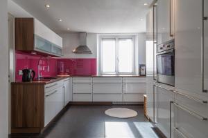 a kitchen with white cabinets and pink walls at Casa Cambodunum in Kempten +25 photos