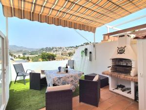eine Terrasse mit einem Tisch, Stühlen und einem Kamin in der Unterkunft Apartamento Alcazar in Almuñécar
