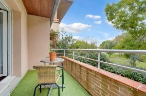 a balcony with a table and chair on a brick wall at Le Jardin des Muses - T3 climatisé avec terrasse, Piscine et Parking in Toulouse