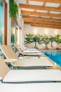 an indoor pool with lounge chairs and a swimming pool at Maramures Retreat & SPA in Poienile Izei