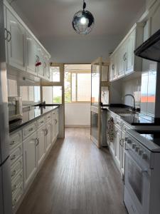 a large kitchen with white cabinets and black counter tops at Ohana Funchal in Funchal