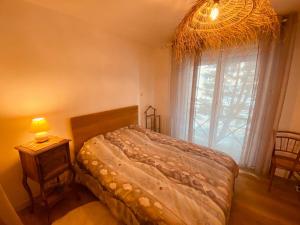 a bedroom with a bed and a window with a chandelier at Le Louisiane in Le Touquet-Paris-Plage