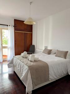 a bedroom with a large white bed with a chair at Ohana Funchal in Funchal +9 photos