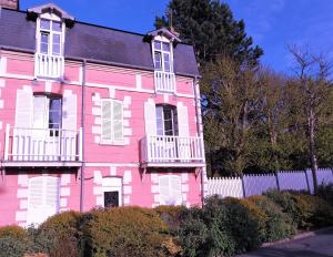a pink house with white windows and a fence at Les Muguets in Villers-sur-Mer