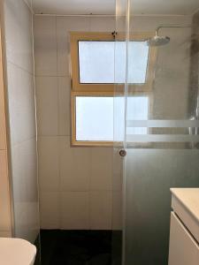 a bathroom with a shower with a window and a toilet at Ohana Funchal in Funchal +9 photos