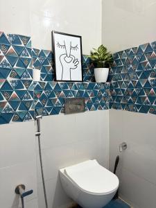 a bathroom with a toilet and a picture on a tiled wall at 1 BHK Upper Tapovan Eternal Stayz in Rishīkesh +18 photos