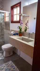 a bathroom with a sink and a toilet and a mirror at Pousada Charme Tiradentes in Tiradentes