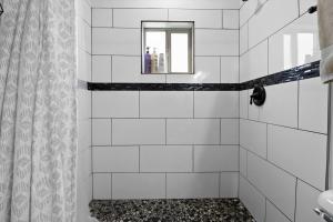 a white tiled shower with a mirror and a window at New Home, Big Views, Hot Tub, Gazebo! - Casa del Sol in Ranchos de Taos +39 photos