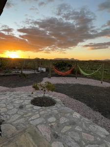 a sunset with a hammock and a tree in a yard at Vila Prana - Chalé Paz - privacidade e vista infinita in Alto Paraíso de Goiás