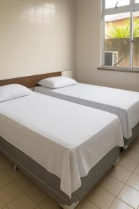 two beds in a room with a window at Hotel Lídia in Fortaleza +8 photos