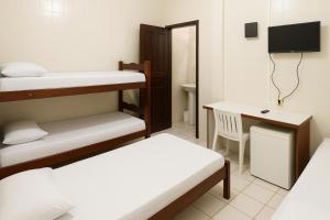 a small room with two bunk beds and a desk at Hotel Lídia in Fortaleza