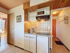 eine kleine Küche mit Spüle und Mikrowelle in der Unterkunft Appartement confortable au pied des pistes avec accès piscine chauffée - FR-1-267-229 in Le Corbier + 13 Fotos