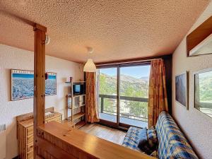 ein Wohnzimmer mit Couch und großem Fenster in der Unterkunft Appartement confortable au pied des pistes avec accès piscine chauffée - FR-1-267-229 in Le Corbier
