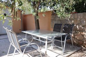 a table and four chairs sitting next to a stone wall at Apartmani California in Starigrad