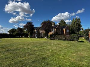 a house with a large field in front of it at Spacious 6-Bed Countryside Home Surrounded by Nature in Sutton Bridge