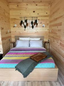 a bed in a room with a wooden wall at Ananda - Enchanted Forest Hideaway in Pleasant Bay