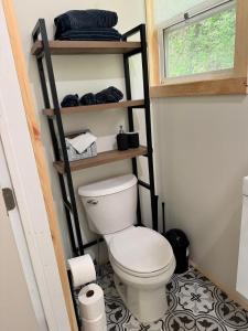 a small bathroom with a toilet and a shelf at Ananda - Enchanted Forest Hideaway in Pleasant Bay +22 photos