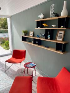 Zimmer mit 2 Stühlen, einem Tisch und Regalen in der Unterkunft L'Abri du Rouget, 5 minutes à pied de la plage du Trez-hir, vacances en famille in Plougonvelin