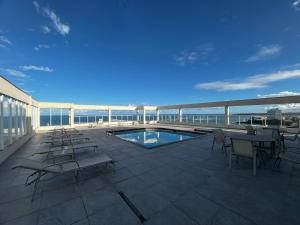 a balcony with chairs and a swimming pool on a building at Areia Flat vista mar piscina e ar in Guarapari