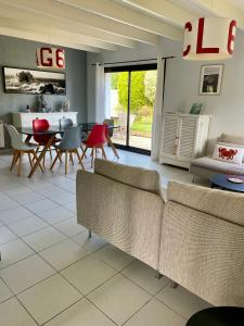 ein Wohnzimmer mit Sofas und einem Tisch und Stühlen in der Unterkunft L'Abri du Rouget, 5 minutes à pied de la plage du Trez-hir, vacances en famille in Plougonvelin