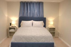a bedroom with a bed with a blue headboard and two lamps at Home beside WEM in Edmonton