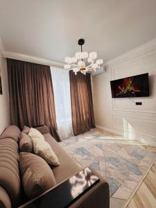 un soggiorno con un divano e un lampadario di Квартира посуточно a Shymkent Altre 11 foto