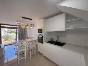 Una cocina con gabinetes blancos y una mesa con sillas. en Las Brisas 38, 2 bedrooms and pool, en San Bartolomé
