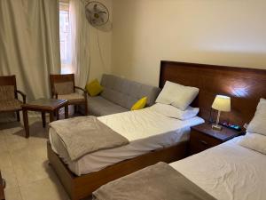 una habitación de hotel con dos camas y un sofá en قرية أكوا فيو الساحل الشمالي - Aqua View El Alamein, en El Qasaba esh Sharqīya 17 fotos más