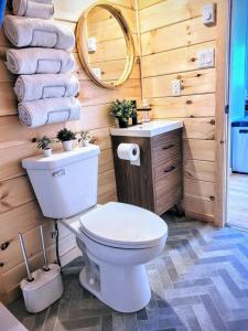 a bathroom with a toilet and a mirror and towels at Beach Cabin 1 in Chéticamp