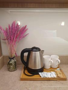 a tea kettle and two cups on a wooden tray at Novotel Acqua Suites Manila by Jolly Luxe in Manila