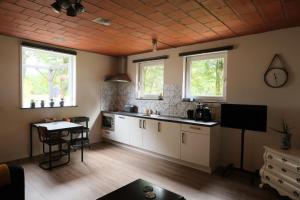 a kitchen with white cabinets and windows and a table at Boerderij de Windroos in Tollebeek +36 photos