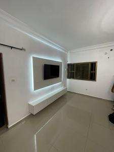 a white living room with a tv on the wall at Maison prive lome in Adéti-Kopé