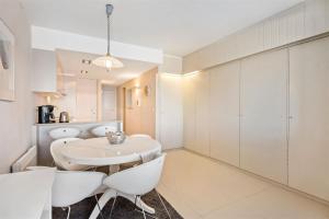 a white kitchen with a white table and chairs at Seaview cosy studio Costa Brava in Blankenberge +4 photos