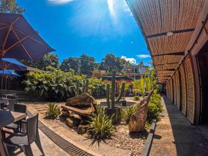 a patio with tables and chairs and an umbrella at Hotel Casa de Hadas in Minca