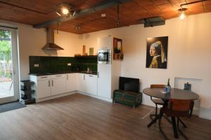 a kitchen with a table and a painting on the wall at Boerderij de Windroos in Tollebeek