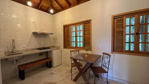uma cozinha com um lavatório, uma mesa e um balcão em POUSADA NICO ON THE HILL em Monte Verde
