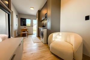 a living room with a white chair in a room at Seu Refúgio Urbano em Criciúma – Lago di Garda Studios in Criciúma