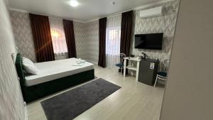 a bedroom with a bed and a desk and a television at Meiman Hotel in Aktobe