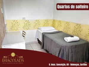 a room with a bed and a table with towels on it at Hotel imaculada in Curitiba
