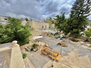 a patio with a table and benches and trees at Beit El Berbara-Pool & Breakfast in Al Ḩulwah