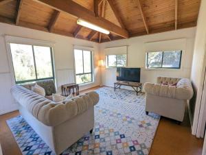 a living room with two couches and a flat screen tv at Sandys Pottery Cottage- pet friendly, wineries, in Healesville