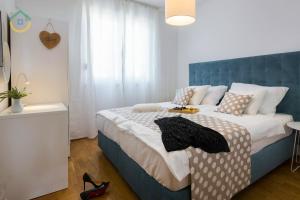 Schlafzimmer mit einem großen Bett mit blauem Kopfteil in der Unterkunft Sun Spalato Views in Split