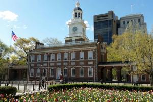 a building with a clock tower on top of it with flowers at Cozy Philly Studio with Free Parking for Long Term Stays in Philadelphia