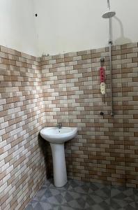 a bathroom with a white sink and a brick wall at Mashingo Homestay in Dar es Salaam