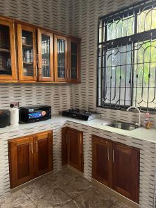 a kitchen with wooden cabinets and a sink and a window at Mashingo Homestay in Dar es Salaam