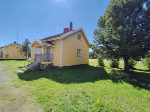 a small yellow house with a tree in the yard at Central Apartment for 4 in Kemi