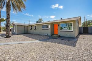 a house with an orange door and a palm tree at Tucson Oasis by Rather Be Properties in Tucson